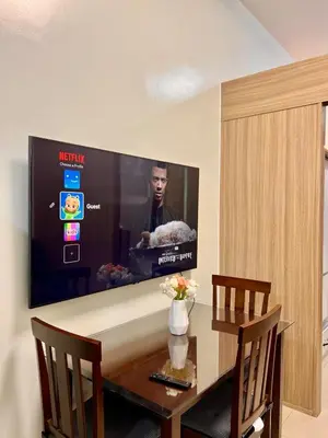 a dining room table with a television on the wall at Airport-side Shore Staycation in Manila