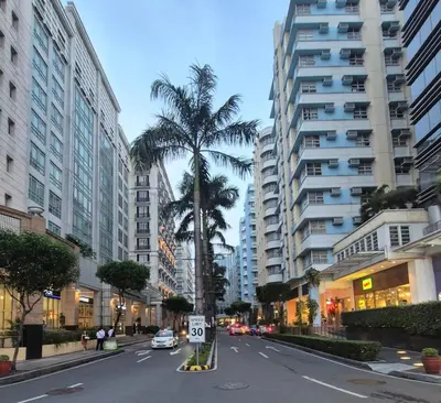 an empty city street with palm trees and buildings at Jacob's Place Near Manila Airport in Manila