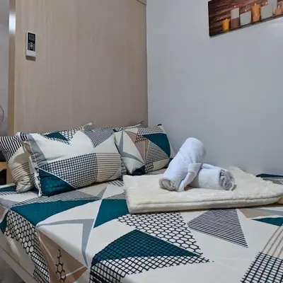 a bed with a dog laying on top of it at MOA Staycation - Sea Residences - Tower C in Manila