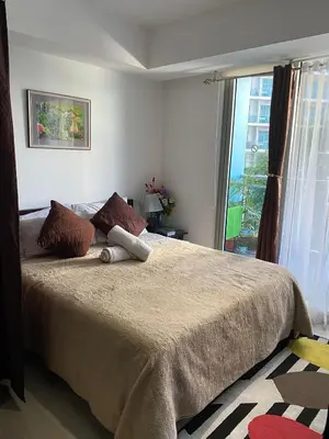 a bedroom with a large bed with a large window at AFFORDABLE STAYCATION NEAR Airport in Manila