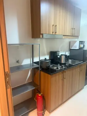 a kitchen with wooden cabinets and a counter top at The Vibe at SMDC The Lush Residences in Manila