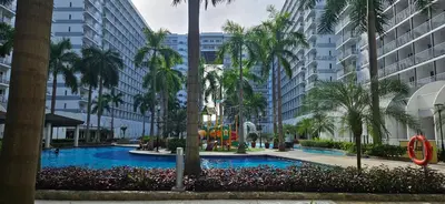 a swimming pool with palm trees and buildings at The Executive Suites by PJTai Realty Shell002 - 1BR in Manila