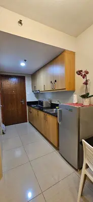a kitchen with wooden cabinets and a stainless steel refrigerator at The Executive Suites by PJTai Realty Shell002 - 1BR in Manila