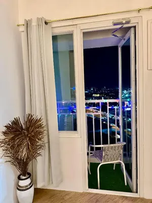 a room with a window with a chair on a balcony at The Global Nest at Anuva Modern 1BR with Pool in Manila