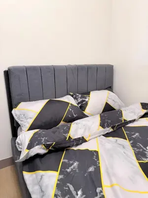 a bed with a black and yellow comforter and pillows at 2 BR Modern Apartment Near the Airport in Manila