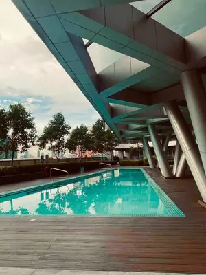 a swimming pool under a large building with at JL's City Hideaway at Fame Residences in Manila