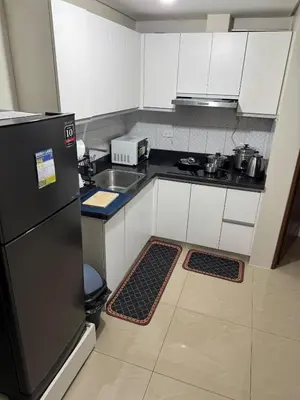 a kitchen with white cabinets and a black refrigerator at Next Abode 1BR at TheBeaconMakati in Manila