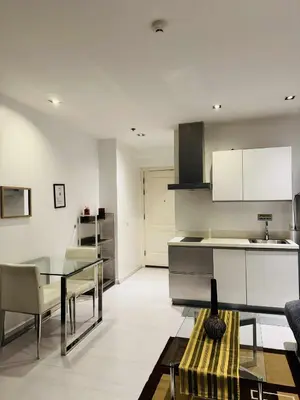 a kitchen with a glass table and a counter top at The Gramercy Residences in Manila