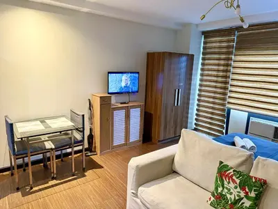 a living room with a couch and a table and a tv at The Gramercy Residences in Manila