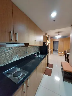 a kitchen with wooden cabinets and a black counter top at Condotel SM MOA sea residences in Manila