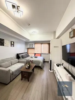 a living room with a couch and a bed and a tv at Cozy Modern Studio Unit with PS4 at The Sentinel Residences, Cubao in Manila