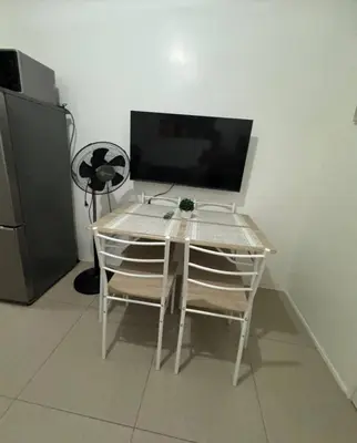 a table with two chairs and a television in a room at At The Shore in Manila
