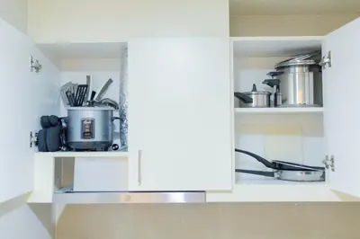 a kitchen with white cabinets with pots and pans at CozyBGCCondoKing BedFast WiFiSteps fromUptownMall in Manila
