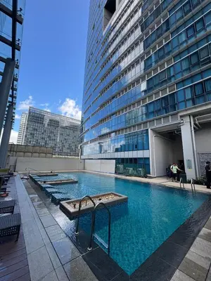 a large swimming pool in front of a tall building at CozyBGCCondoKing BedFast WiFiSteps fromUptownMall in Manila