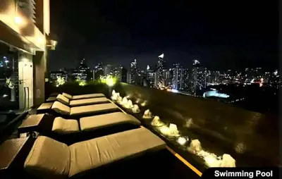 a rooftop lounge with a view of the city at night at The Gramercy Residences by YYESS in Manila