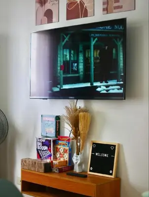 a tv hanging on a wall above a wooden table at Secret Nest in Manila