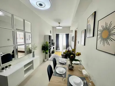 a dining room with a table and a living room at Condo Transient by Eugenio Tan in Manila