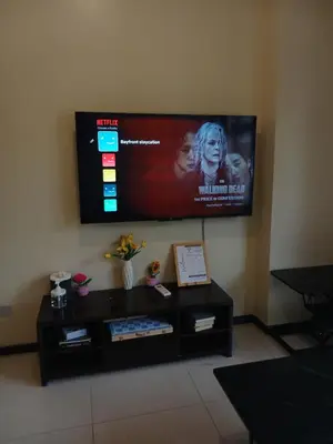 a flat screen tv on a wall above a table at Bayfront Suite near Airport, MOA, PICC, Star City, OKADA With Fast WIFI & Netflix Free Pool Access in Manila
