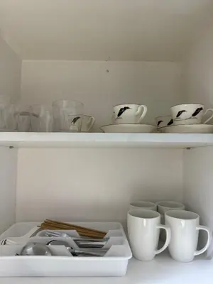 a white shelf with cups and dishes on it at stylish 2BR Condo Near NAIA in Manila