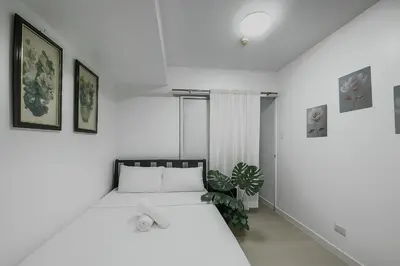 a white bedroom with a bed and a plant at Cheapest staycation miami tower azure in Manila