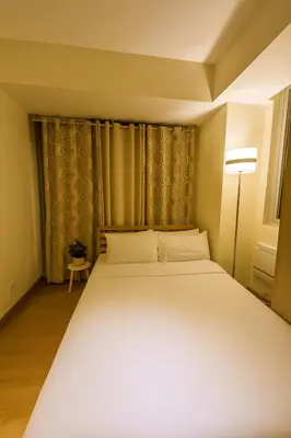 a bedroom with a large white bed and a lamp at Cheapest staycation miami tower azure in Manila