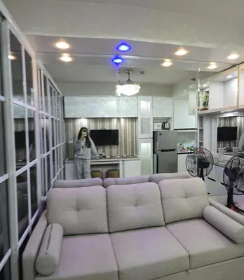 a woman standing in a living room with a couch at 1BR Deluxe Suite pool view with Balcony in Manila
