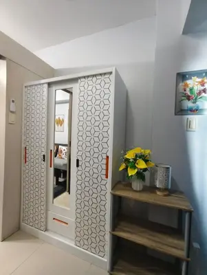a room with a mirror and a vase with flowers at Juliza's MOA Staycation in Manila