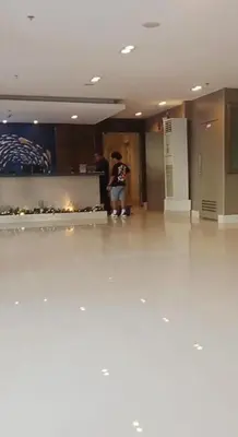 a person standing in a lobby with a fireplace at Woodox Condotel in Manila