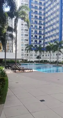 a park with benches and palm trees in front of a building at Woodox Condotel in Manila