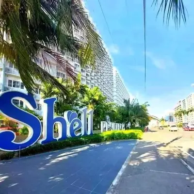 a sign in front of a building with palm trees at Ben's stay cation in Manila