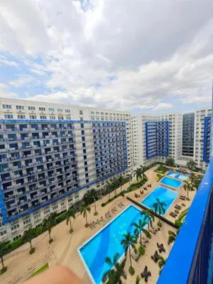 a view of a large building with a pool and palm trees at Rooms near Aiport - Credit Card accepted 0995 - 448 - 8872 in Manila