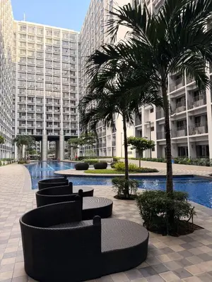 a courtyard with chairs and palm trees in a building at Pool View Condo near NAIA, SMX Netflix, WiFi, PS4 in Manila