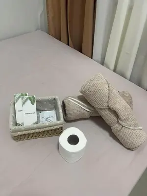 a basket of toiletries and a roll of toilet paper on a bed at Cozy Haven Staycation in Manila