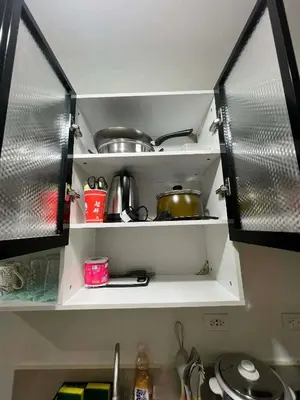 a kitchen with open shelves with pots and pans at Transient Home by Molave in Manila