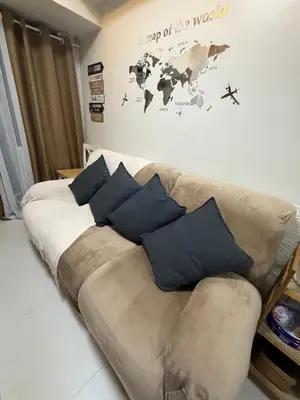 a couch with blue pillows in a living room at Shore Bliss Staycation by Aims in Manila