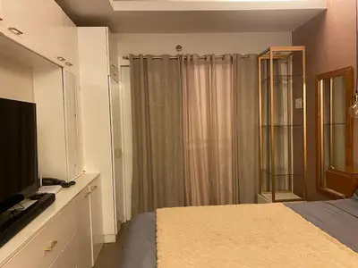 a bedroom with a bed with a tv and a window at Affordable, Cozy & Quiet 1BR in BGC - Ideal for Short & Long Stays in Manila