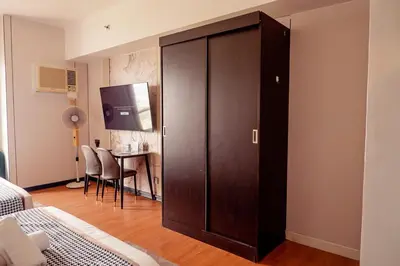 a large brown cabinet in a room with a table at Elegant Condo at ETON Baypark Manila in Manila