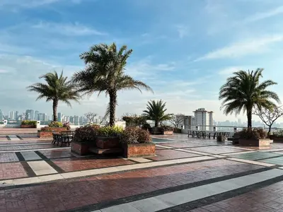 a courtyard with palm trees and benches and a city at Stylish & Serene Penthouse in Manila
