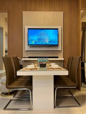 a dining room with a table and chairs and a tv at Stylish & Serene Penthouse in Manila
