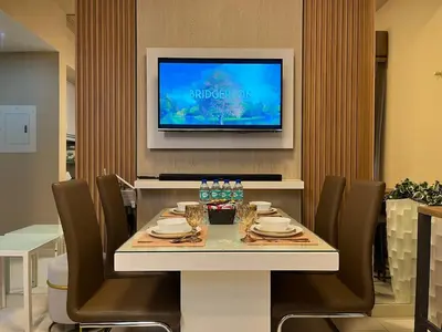 a dining room with a table with chairs and a television at Stylish & Serene Penthouse in Manila