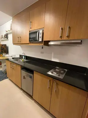a kitchen with wooden cabinets and a microwave at Shell Residences Condo in Manila