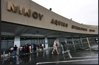 a man pulling a luggage cart in front of an airport at Shore Residences in Pasay Manila, near Mall of Asia and Manila Airport in Manila