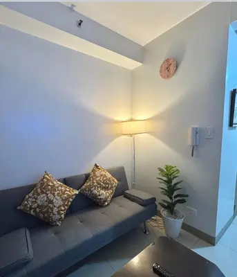 a living room with a couch and a clock on the wall at Pasay Manila Condominium Rentals, walking distance to Mall of Asia and near in Manila airport, located in Shore Residences Seaside Boulevard in Manila