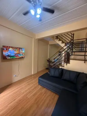 a living room with a couch and a staircase at Apt101 Guest House in Bacoor