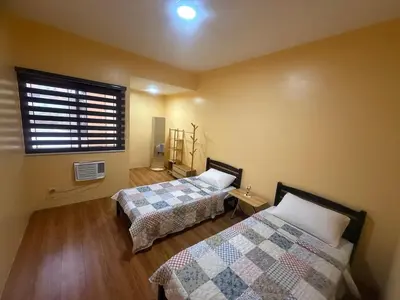 a bedroom with two beds and a window with a window at Apt101 Guest House in Bacoor