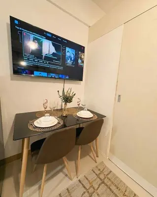 a dining room table with two chairs and a tv on the wall at Condo with Sunset View in Manila