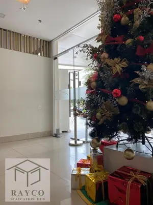 a christmas tree in a lobby with presents at Cozy Escape with Golden Hour View Condo in Manila