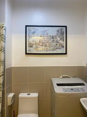 a bathroom with a painting on the wall above a toilet at Stunning Pool and City View in Manila