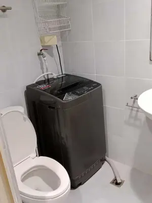 a bathroom with a toilet and a black trash can at Sea Residences Golden escape condotel in Manila