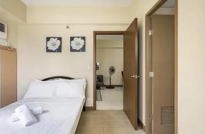 a bedroom with a bed with white sheets and towels at 1 Bedroom Apartment Condo Across Manila Airport NAIA T3 in Manila